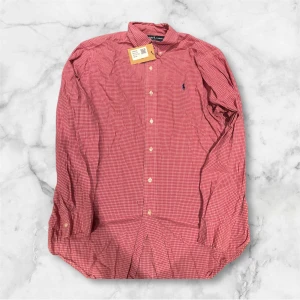 Rutig röd skjorta från Polo Ralph Lauren - Snygg röd skjorta från Polo Ralph Lauren med klassiskt rutigt mönster och broderad logga på. Väldigt bra skick. Perfekt för dig som gillar stilrena och tidlösa plagg. Classic fit. Passar S/M