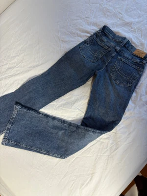 Blå bootcut jeans från Perfect Jeans - Snygga blå bootcut jeans från Perfect Jeans med coola vita sömmar på bakfickorna. Klassisk femficksmodell i mjukt jeanstyg, perfekt för dig som gillar en tidlös look med lite extra edge. Passar dig som vill ha jeans med lite utsvängda ben. Endast använda 2 ggr! 200kr
