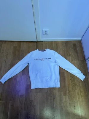 Vit sweatshirt Tommy Hilfiger XS - Säljer en clean vit sweatshirt från Tommy Hilfiger i storlek XS. Tröjan har rund hals, långa ärmar och klassisk logga broderad framtill samt liten flagga på ärmen. Tillverkad i mjuk bomull för skön vardagsstil.