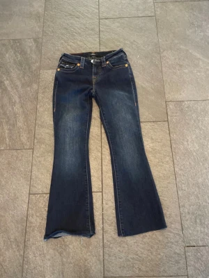 Blå bootcut jeans från True Religion - Märke: True religion                                    Modell: Becca mid Rise bootcut            Storlek: 23 (obs uppsydda i längd 82 cm för att passa, hon är 150 cm lång)                                                 Skick: ej använda endast tvättade en gång 