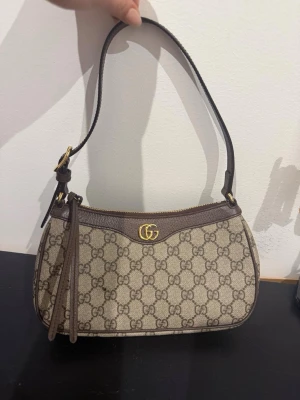 Gucci Ophedia axelväska beige monogram  - (Inte en fläck, det är ludd ser jag nu) väska från Gucci i beige och brunt med klassiskt monogram, detta var en present serienummer finns självklart men jag känner att det är dax för den att hitta ett hem där den blir uppskattad då den inte riktigt är min stil när det kommer till väskor.. prioriterar en snabb och seriös affär över priset så jag kan gå ner rätt rejält i pris isf, prissättningen jag har nu är för att sola ut oseriösa köpare. skickar iväg den direkt väl paketerad med omsorg. 