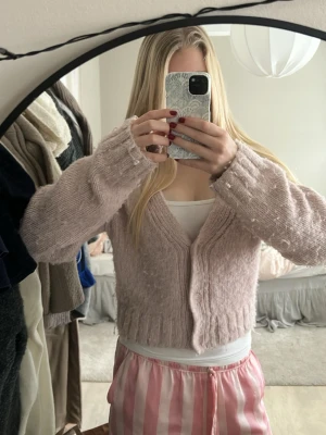 Ljusrosa stickad kofta med v-ringning - Mysig ljusrosa stickad kofta med v-ringad hals och knappar framtill. Koftan är croppad och har långa ärmar med ribbade muddar❣️❣️ Perfekt att slänga på sig när det är lite kyligt. Superfin färg och mjukt material💓💓