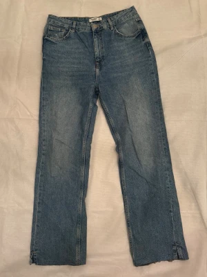 Pull&Bear jeans  - Säljer ett par klassiska blå jeans från Pull&Bear med rak passform och fem fickor. Jeansen har hög midja, bälteshällor och dragkedja med knapp. Materialet är slitstarkt denim i bomull och benen har en enkel, rak siluett.