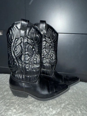 Svarta cowboy boots  - Säljer ett par svarta cowboy boots med snygga broderade detaljer och spetsig tå. 