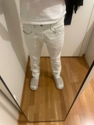 Replay Hyperflex Anbass vita jeans - Snygga vita Replay Hyperflex Anbass jeans med klassisk femficksdesign och stretchigt material. De har raka ben, normal passform och detaljer som metallnitar och läderpatch bak. Perfekta för dig som vill ha stilrena och bekväma jeans. Lite smutsiga annars inga defekter.