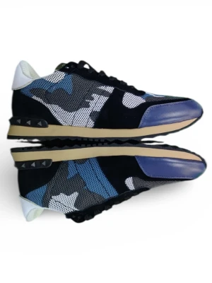 Valentino Garavani Rockrunner sneakers - Säljer ett par Valentino Garavani Rockrunner sneakers med blå, svart och vit camouflage-mönster. Skorna har snörning, platt sula och detaljer i mocka och skinn. Tåpartiet är rundat och har blått skinn, medan hälen är vit med nitar på sulan. Box medföljer.