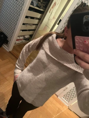 Beige stickad offshoulder tröja - Säljer en beige stickad tröja med bred offshoulder-krage och ribbade detaljer vid hals, ärmslut och nederkant. Tröjan har lång ärm och är perfekt för dig som gillar en chill och snygg look. Supermjuk och skön att ha på sig.