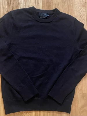 Merinoulltröja från Riley - Klassisk svart tröja från Riley i mjuk merinoull. Rund halsringning och långa ärmar med ribbade muddar. Stilren och har krympt lite, passar storlek XS/S