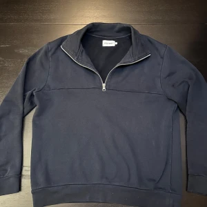 Mörkblå half zip tröja East West - Snygg mörkblå långärmad tröja från East West med half zip-dragkedja i halsen. Tröjan har en klassisk och enkel design.