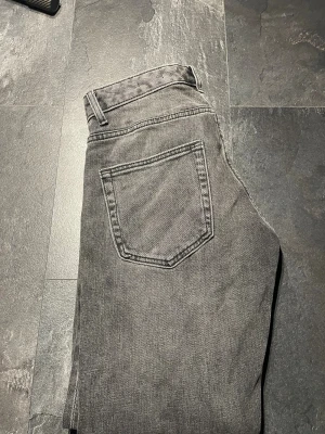 Grå jeansbyxor från Dressmann - Snygga grå jeansbyxor från Dressmann i regular fit. Klassisk femficksmodell med raka ben och normal passform. Perfekt för dig som gillar enkel och stilren look. Materialet är slitstarkt jeans och färgen är mörkgrå.