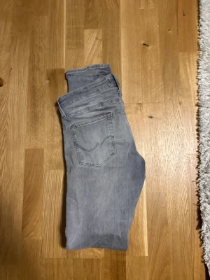 Jack & Jones slim Glenn Jeans - Säljer ett par grå Jack and jones jeans med slim fit och klassisk femficksdesign. Jeansen har en snygg tvättad look, raka ben och diskreta sömmar på bakfickan. Perfekt för dig som gillar stilrena och bekväma jeans.
