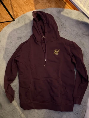 Vinröd SikSilk hoodie - Säljer just nu min vinröda siksilk hoodie som jag aldrig använt eftersom har glömt bort. Vill ba bli av med den så skriv vid fler frågor!!