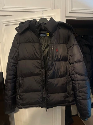 Svart pufferjacka från Polo Ralph Lauren - Säljer helt ny och oanvänd Ralph Lauren-jacka i storlek L. Jackorna är varma, stilrena och passar både till vardags och finare tillfällen. Originaletiketter sitter kvar. Finns för snabb affär!  💯 Skick: Helt ny (oanvänd) 📏 Storlek: L 🎨 Färg: Svart (andra färger kan ev. finnas – fråga gärna!) 👕 Passform: Unisex