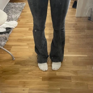 Mörkgrå bootcut jeans med rå kant - Snygga mörkgrå jeans med bootcut passform och rå, fransig kant längst ner. Jeansen har klassiska fem fickor och dragkedja fram. Materialet är jeans och färgen är tvättad mörkgrå, vilket ger en cool och avslappnad vibe.