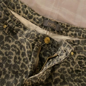 Leopardmönstrade shorts - Snygga shorts från Milla i leopardmönstrat denimtyg. De har klassisk femficksdesign, uppvikta benslut, gylf med dragkedja och knapp samt bälteshällor. Perfekta för dig som vill sticka ut med ett djurmönster i garderoben.