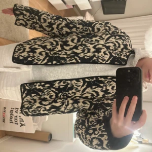 Svart och beige quiltad jacka från Zara - Quiltad jacka från Zara i svart och beige med unikt mönster. Jackan har lång ärm, normal passform och knäppning framtill. Den är köpt för ca 6 månader sedan och har endast används ett par gånger, därför inga tecken på användning. 