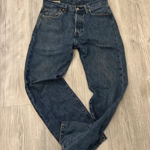 Levi's 501 blå jeans straight fit - Klassiska Levi's 501 jeans i blå tvätt med rak passform och fem fickor. Jeansen har knappgylf och är tillverkade i slitstarkt bomullsjeansmaterial. Perfekta för dig som gillar tidlös stil och vill ha ett par jeans som alltid funkar.