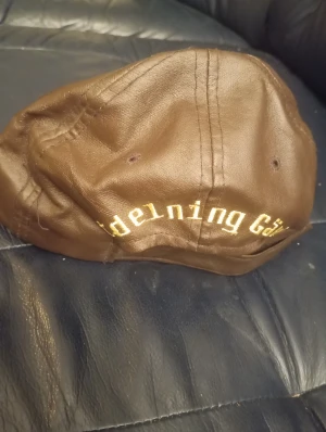 Posten keps läderlook med broderad logga - Snygg brun Posten keps läderlook  Klassisk form med böjd skärm och ventilerande hål. Perfekt för dig som vill sticka ut med en unik accessoar.