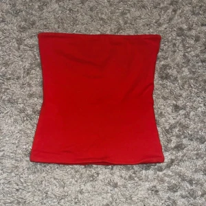 Röd bandeau tubtopp från Bik Bok - Säljer en röd bandeau tubtopp från Bik Bok i storlek S. Toppen är axelbandslös och har en enkel, tight passform som sitter snyggt mot kroppen. Materialet är mjukt och stretchigt
