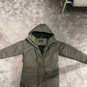 Peak Performance Jacka   - Säljer en olivgrön dunjacka från Peak Performance i storlek S. Jackan har huva, två stora fickor med lock framtill och dragkedja. Insidan är svart och quiltad för extra värme. Riktigt varm och är perfekt nu för vintern. Vid funderingar hör av er! 