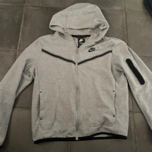 Grå Nike tech hoodie - Säljer nu en tvär fett Nike tech tröja i storlek XL i barnstorlek som passar runt  160-170 som motsvarar till XS🙌🏼. Skriv för fler frågor🫡Pris kan diskuteras✅