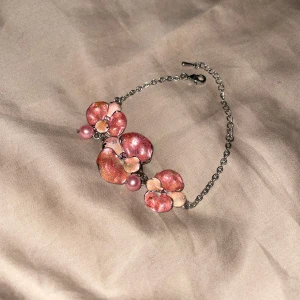 Rosa blommigt armband med pärlor - Säljer ett superfint armband med rosa blommor och pärlor. Blommorna har en skimrande yta och armbandet är i metall med justerbar kedja. Perfekt för att piffa upp en outfit till fest eller vardag! 🌸✨ pris går att diskutera 💖