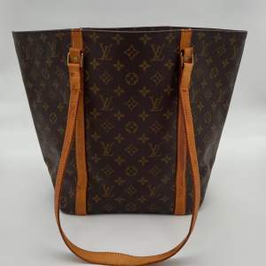 Louis Vuitton Monogram Sac Shopping Bag  Skick: C, väldigt fint vintage skick, bristningar i lädret på bandet syns ej lika mycket när väskan bärs. Se alltid bilder för egen uppfattning.  Serienummer: MB0030  Sku: V001  Mått: B25-50cm x H33cm x D14cm 