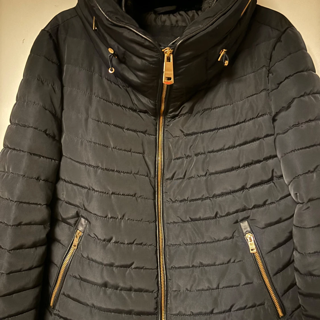Svart pufferjacka med gulddetaljer