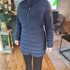 Mörkblå dunjacka Bondelid - Säljer en snygg mörkblå dunjacka i längre modell. Jackan har en dragkedja framtill och praktiska fickor med dragkedjor. Perfekt för kyliga höst- och vinterdagar. Den är långärmad och har en normal passform. Superbra skick och redo för nya äventyr!