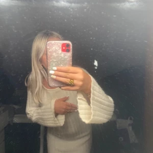 Vit stickad klänning - Mysig vit stickad klänning med långa ärmar och en tight passform. Perfekt för höst och vinter, den är både stilren och bekväm. Klänningen har en enkel design som gör den lätt att matcha med olika accessoarer.