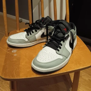 Nike Air Jordans i grått och svart - Säljer ett par Nike Air Jordans i mycket bra skick. Skorna är grå och svarta med vita detaljer och har den klassiska Air Jordan-loggan i rött på baksidan. Perfekta för både vardag och finare tillfällen. Kan bytas mot ett par Air force 1 