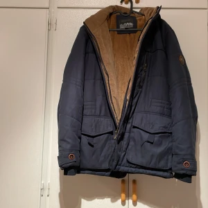 Mörkblå vinterjacka med teddyfoder - Säljer en mörkblå vinterjacka med mysigt teddyfoder. Jackan har dragkedja och knappar, samt flera praktiska fickor. Perfekt för kalla vinterdagar! 🧥❄️