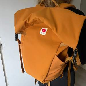 Ockra orange stor och rymlig ryggsäck från Fjällräven i modellen är Ulvö rolltop. Endast använd 1 gång, så den är helt i nyskick! Perfekt för vandring eller vardagsbruk. Den har justerbara vadderade axelremmar och ett rymligt huvudfack. Tillverkad i slitstarkt material med en stilren design. Kolla gärna in Naturkompaniets hemsida för mer information om ryggsäcken! Bara att skriva om du har frågor eller vill ha fler bilder på väskan☺️