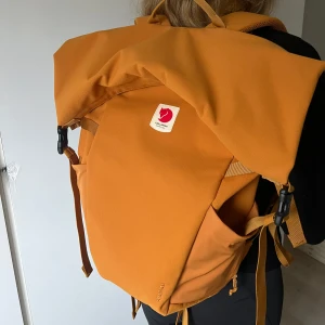 Orange ryggsäck från Fjällräven - Ockra orange stor och rymlig ryggsäck från Fjällräven i modellen är Ulvö rolltop. Endast använd 1 gång, så den är helt i nyskick! Perfekt för vandring eller vardagsbruk. Den har justerbara vadderade axelremmar och ett rymligt huvudfack. Tillverkad i slitstarkt material med en stilren design. Kolla gärna in Naturkompaniets hemsida för mer information om ryggsäcken! Bara att skriva om du har frågor eller vill ha fler bilder på väskan☺️