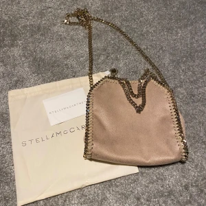 Stella McCartney väska✨✨ - Beige/rosa stella maccartney väska i storleken tiny. Fick den för något år sedan på min födelsedag och är fortfrande i väldigt fint skick. Se en liten fläck på bild 4, färgen på en av kejdjorna börjat tappa den guldiga färgen lite. Dustbag, tag medfö
