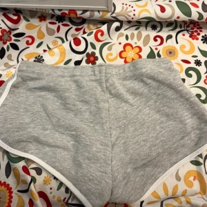 Grå shorts med snörning - Säljer ett par grå shorts från newyorker med vit snörning i midjan.. Shortsen har en mjuk känsla och är kantade med vita detaljer. Bra skick, strl xs