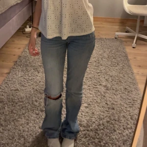 Blå jeans med slitningar - Snygga blå jeans med slitningar på knäna. De har en klassisk passform och är perfekta för en avslappnad stil. Jeansen har en rak design och är ett måste i garderoben.