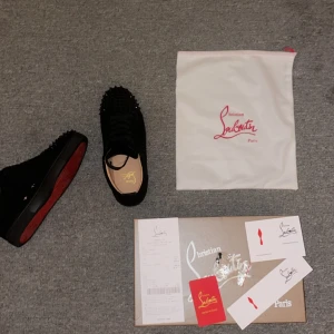 Svarta sneakers från Christian Louboutin - Snygga svarta sneakers från Christian Louboutin i mocka med ikoniska röda sulor. Skorna har dekorativa nitar på ovansidan som ger en edgy look. Perfekta för den som vill sticka ut med stil polisen tog dem så dem tog mitt kvitto också dem behövs ba tvättas lite sen ser dem så gott som nya ut
