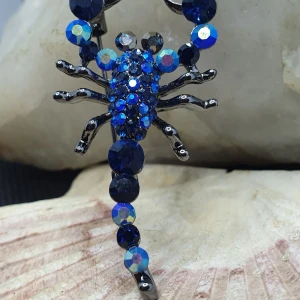 Brosch - Hummer i blått och svart - Den här broschen föreställer en hummer och måtten är ca 4.5 ×2.5 cm. Svartmetallic färgad metall med vacker ytstruktur och ytan täckt av kristaller I flera färger.  Otroligt vacker brosch.