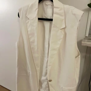 Vit väst med knappar - Elegant vit väst med knappar och klassisk krage. Perfekt för att lägga till en stilren touch till din outfit.