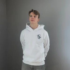 Vit hoodie med tryck - Säljer en stilren vit hoodie med ett svart tryck på bröstet. Hoodien har en klassisk passform med känguruficka och ribbade muddar vid ärmslut och nederkant. Perfekt för en avslappnad look.