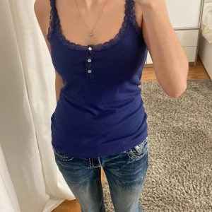 Blå linnetopp från Hunkemöller - Säljer en blå linnetopp från Hunkemöller med spetsdetaljer och knappar framtill. 