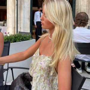 Blommig topp från MNG - Säljer en vacker blommig topp från mango med tunna axelband och ett glittrigt mönster i guld. Perfekt för sommarens alla tillfällen.