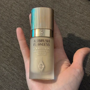 Airbrush Flawless Foundation - Säljer en flaska Airbrush Flawless Foundation från Charlotte Tilbury i nyansen 6 Neutral. Denna foundation ger en jämn och felfri finish med lång hållbarhet. Flaskan har en elegant design med guldfärgat lock.