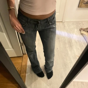 Grå jeans från Ma Fashion - Snygga grå jeans från Ma Fashion med broderade detaljer på bakfickorna. De har en låg midja och en flare passform, perfekt för en avslappnad stil. Jeansen har klassisk femficksdesign och stängs med dragkedja och knapp.