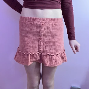 Rosa kjol från Primark - Söt rosa kjol från Primark med volangdetaljer och knappar framtill. Tillverkad i ett mjukt och bekvämt material. Storleken är 6-7 år men då den där väldigt stretchig passar den även på äldre barn! Säljer den för att den inte passar mig längre! OBS, kjolen har en mycket liten fläck vid knapparna, men den lägger man inte märke till!💗