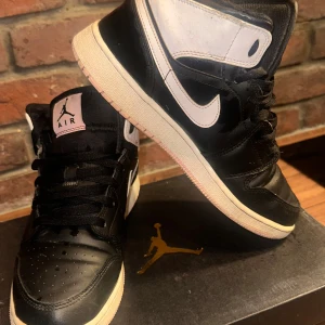 Svarta och vita Nike Air Jordans - Snygga svarta och vita med rosa detaljer Nike Air Jordans med klassisk design. Perfekta för en sportig och stilren look.