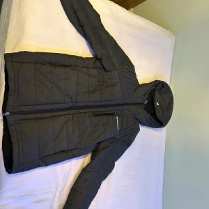 Grå quiltad jacka med huva - Säljer en grå quiltad jacka från Peak Performance. Jackan har en praktisk huva och dragkedja framtill. Perfekt för kyligare dagar. Pris kan diskuteras vid snabb affär😀