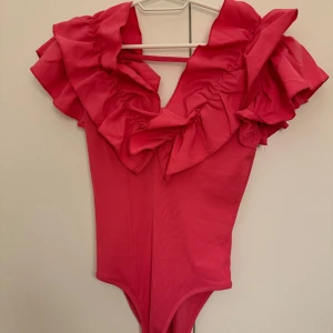Volang bodysouit - Rosa ribbad bodysuit med v ringad volang både fram och bak<3