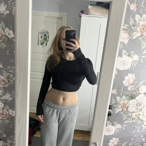 Svart croppad topp med snörning - Snygg svart croppad topp med långa ärmar och trendig snörning i ryggen. Perfekt för en stilren look.